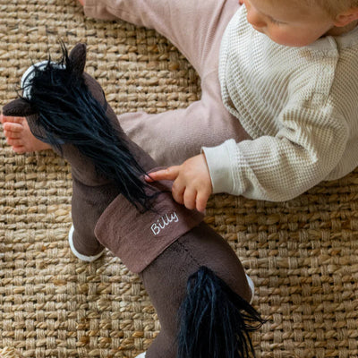 Child playing with a toy horse on a textured floor
