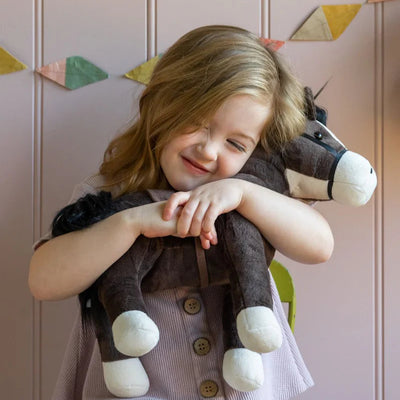 Child holding a plush horse toy against a wall with geometric decorations
